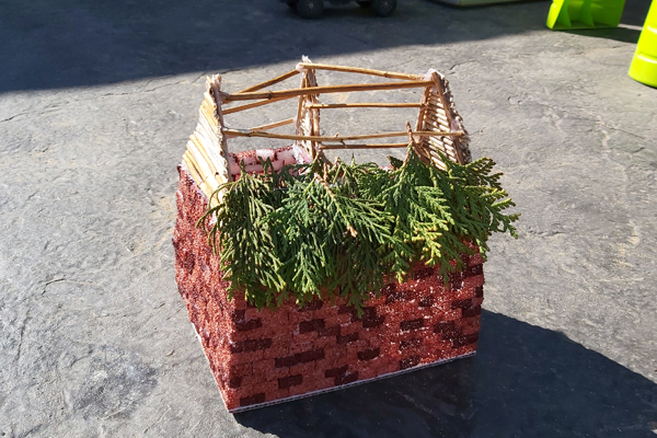 building the roof of a fairy house with plant stalks and ceder leaves 