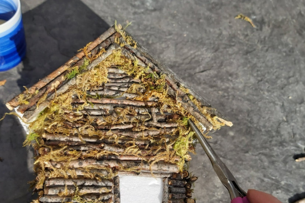 adding moss to fill the gaps on the diy twig fairy house