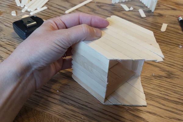 gluing the popsicle stick house together