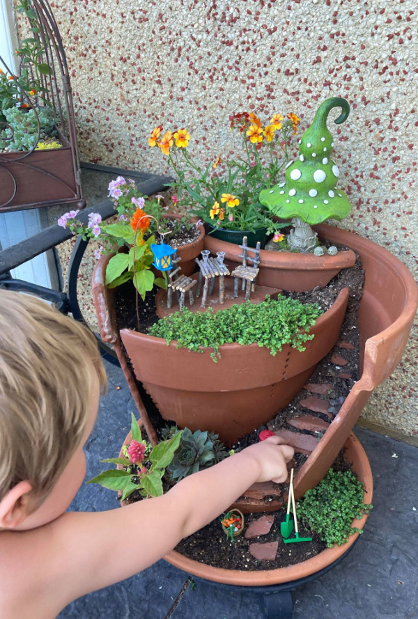 child playing with broken pot fairy garden